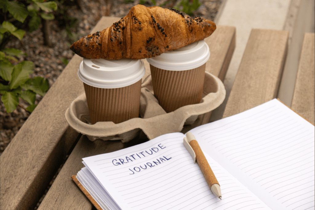 an image for 7 Best Intention-Setting Prompts To Kickstart Your Day with Purpose showing breakfast and a gratitude journal