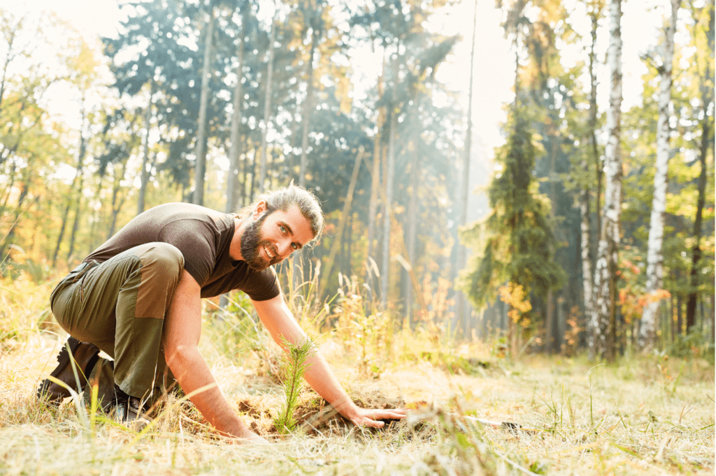 image featured in Must Know: 11 Popular Eco-Friendly Terms And Their Meanings showing a man planting a tree in a forrest