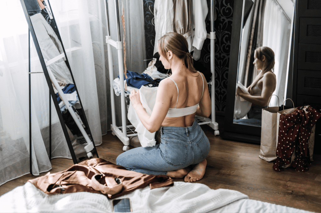 image featured in 23+ Simple Ways to Declutter Your Home (Once and For All!) showing a young woman decluttering her closet