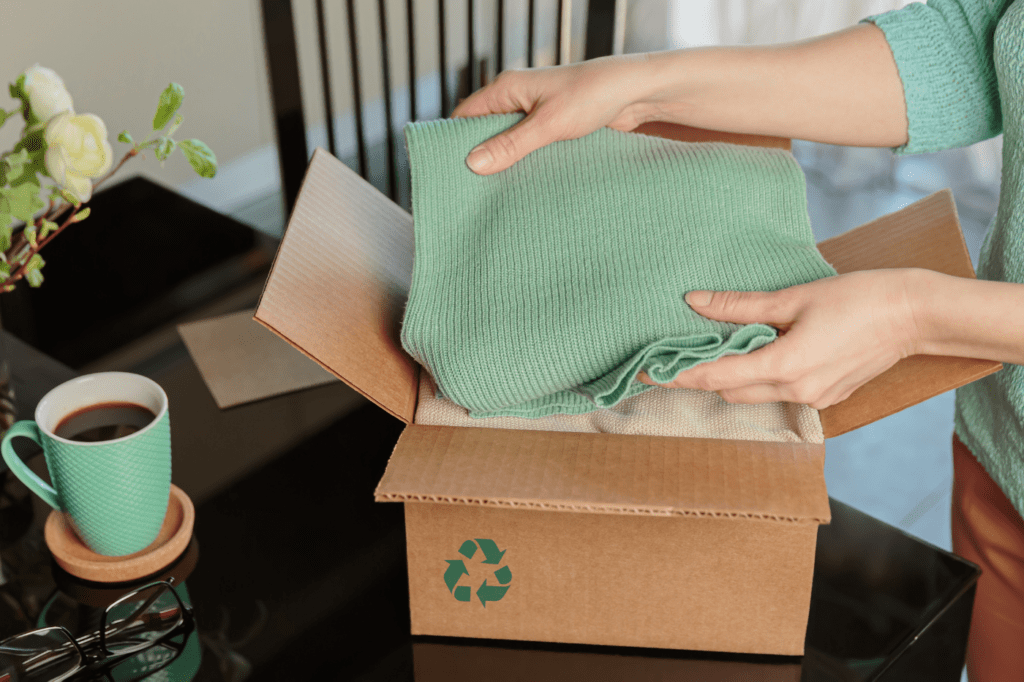 woman putting clothes in a box with a recycle symbol on it